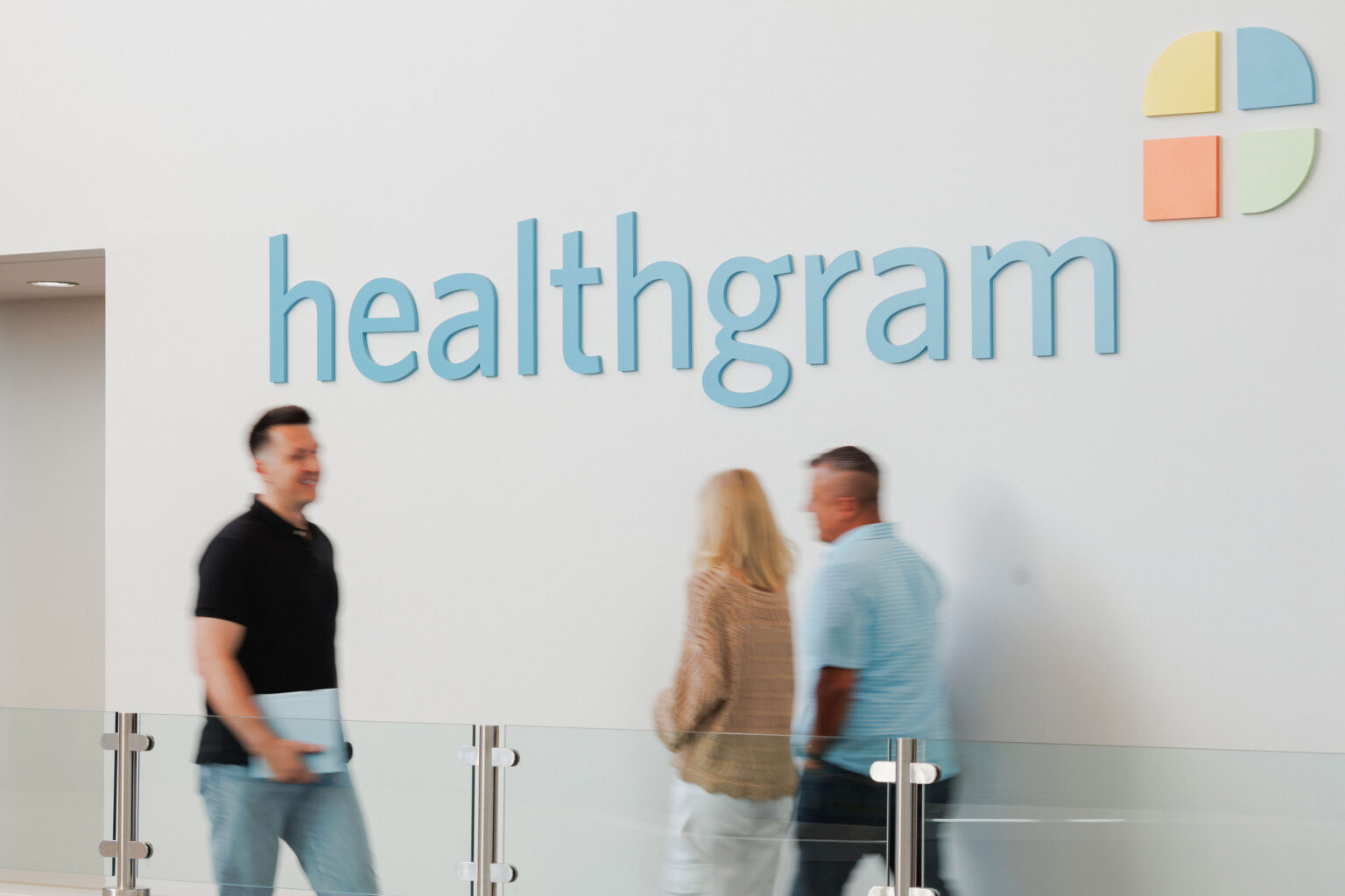 Healthgram employees walking by the Healthgram logo, representing healthcare solutions and health plan administration.