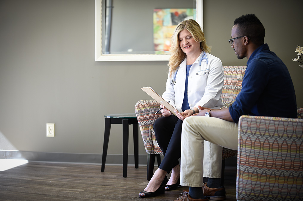 Female doctor and male patient in a Healthgram clinic reviewing paperwork