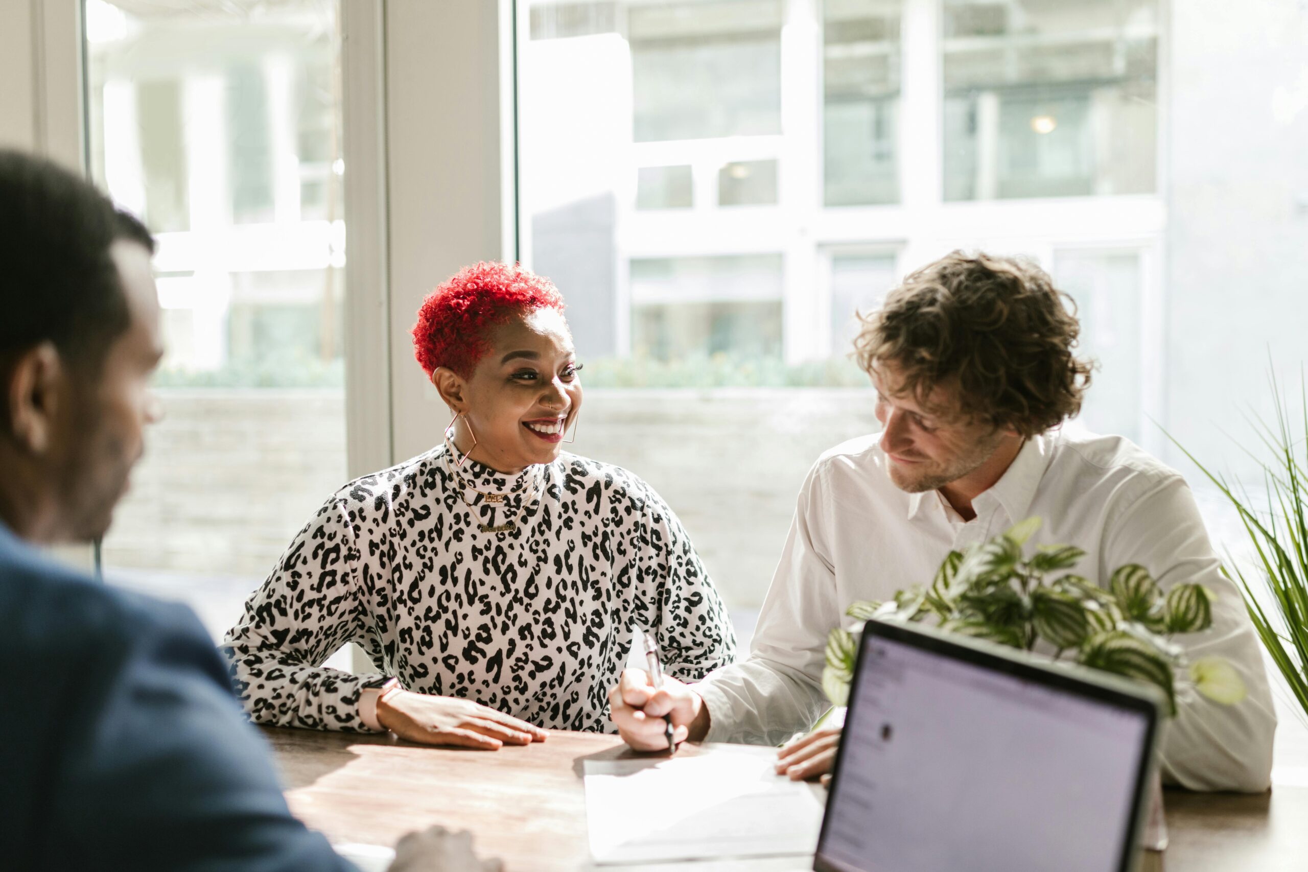 Three employees talking around a conference table